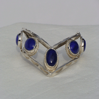 Five fouteen by ten millimeter oval Blue Lapis stones bezel set connected by two triangular wires which are formed to a chevron shape. Worn with chevron pointing down